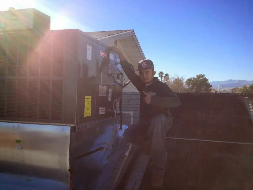 HVAC technician performing Air Duct Cleaning on a rooftop unit in Center